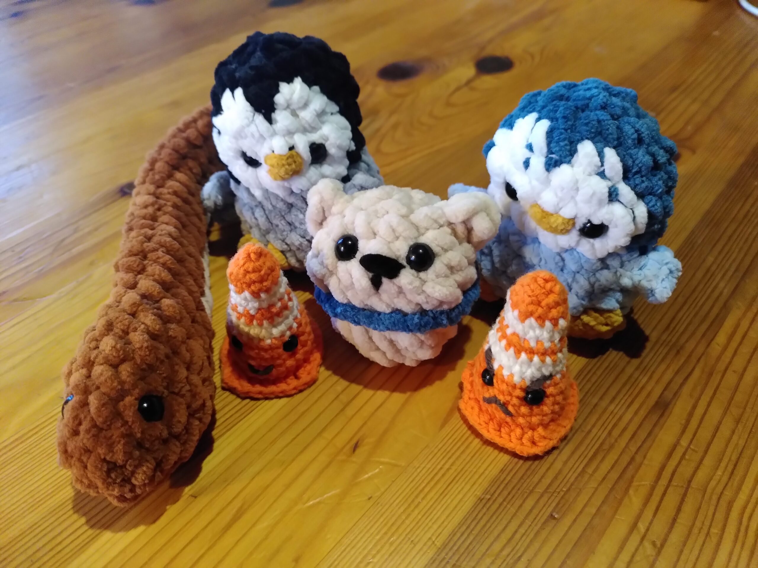 Plusieurs petits personnages en crochet, les uns à coté des autres. Il y a un serpent, deux manchots, un ours blanc, et deux plots de chantier.